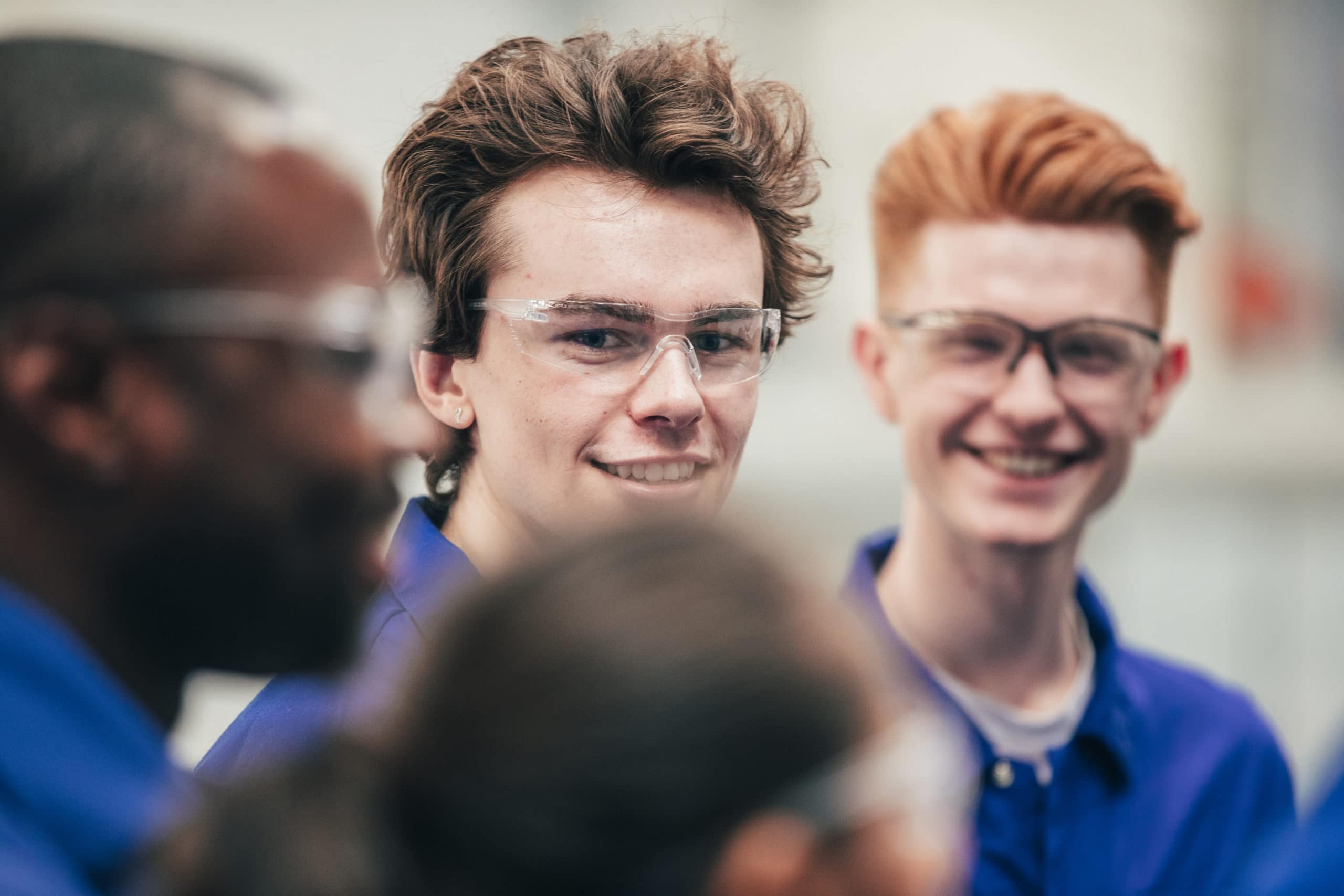 Gruppe Auszubildender mit Schutzbrille und blauem Kittel